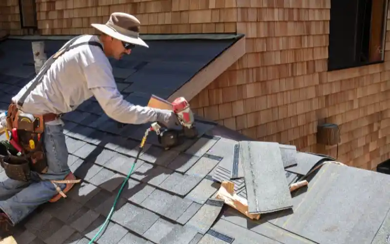 worker installing shingles on roof